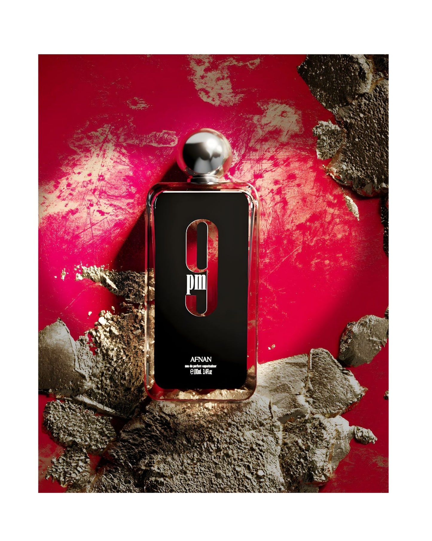 A dramatic overhead shot of a rectangular glass bottle of Afnan 9 PM Eau de Parfum, 100ml / 3.4 fl.oz., resting on a heavily textured, vibrant red and gold surface. The black label with the large white "9 PM" graphic is centered, and the silver spherical cap is visible at the top.