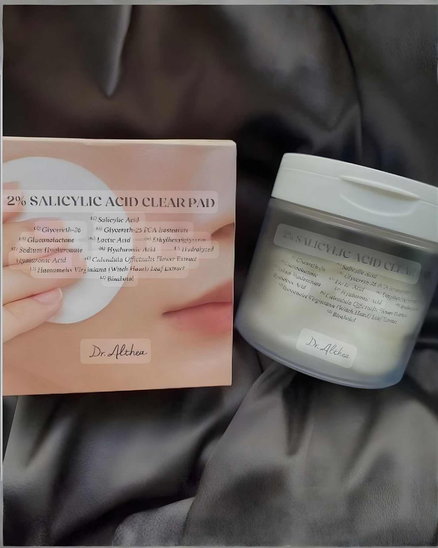 Close-up of the Dr. Althea 2% Salicylic Acid Clear Pad box and jar. The box's label lists key ingredients like Salicylic Acid, Lactic Acid, and Witch Hazel Extract.