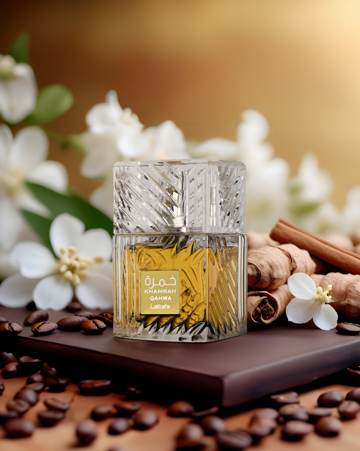 Khamrah Qahwa Lattafa perfume bottle on chocolate with coffee beans, cinnamon, and white flowers, showcasing rich Arabian scents