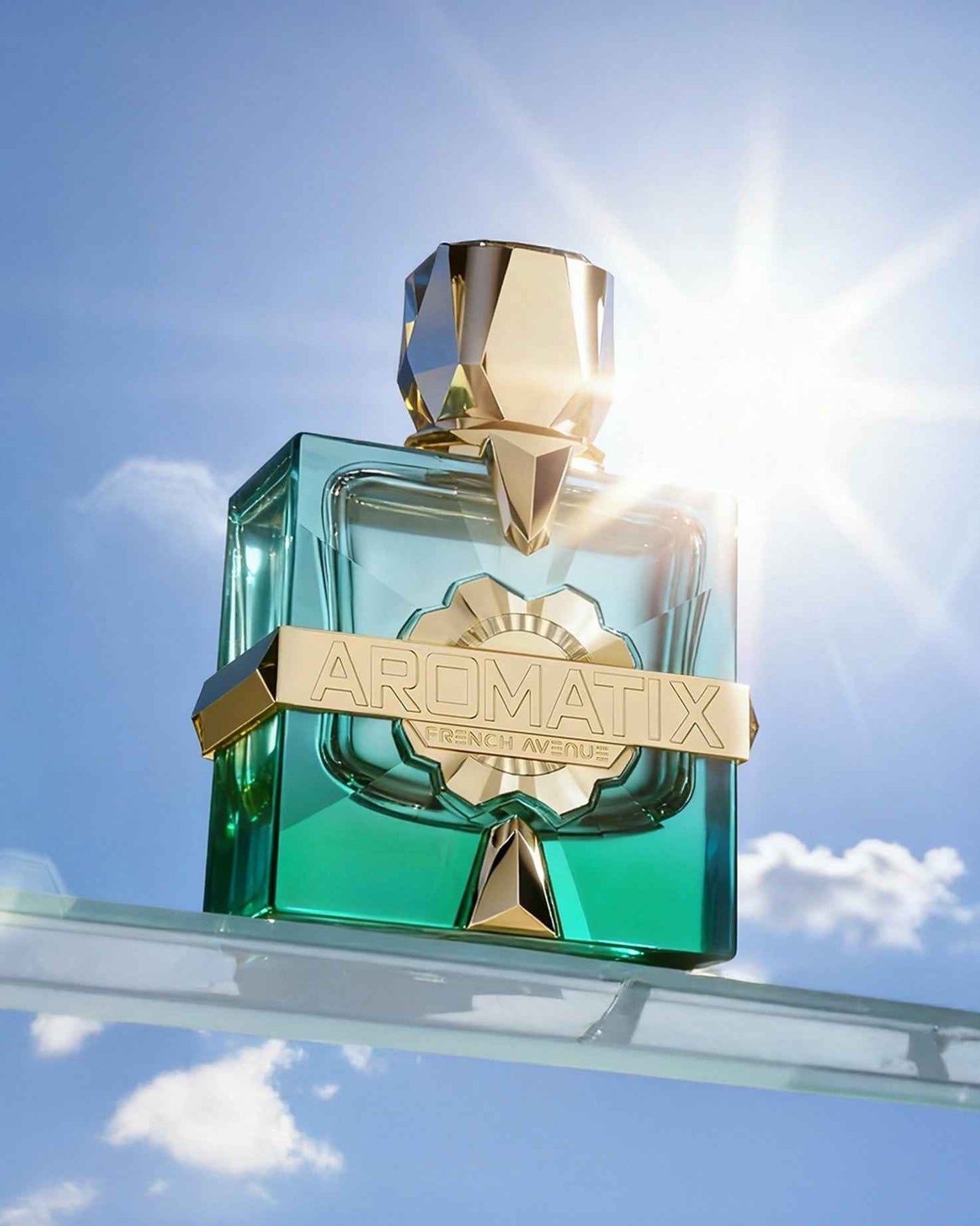 French Avenue Aromatix Sun Kissed ExDP perfume bottle held against a bright blue sky with natural sunlight creating a lens flare effect