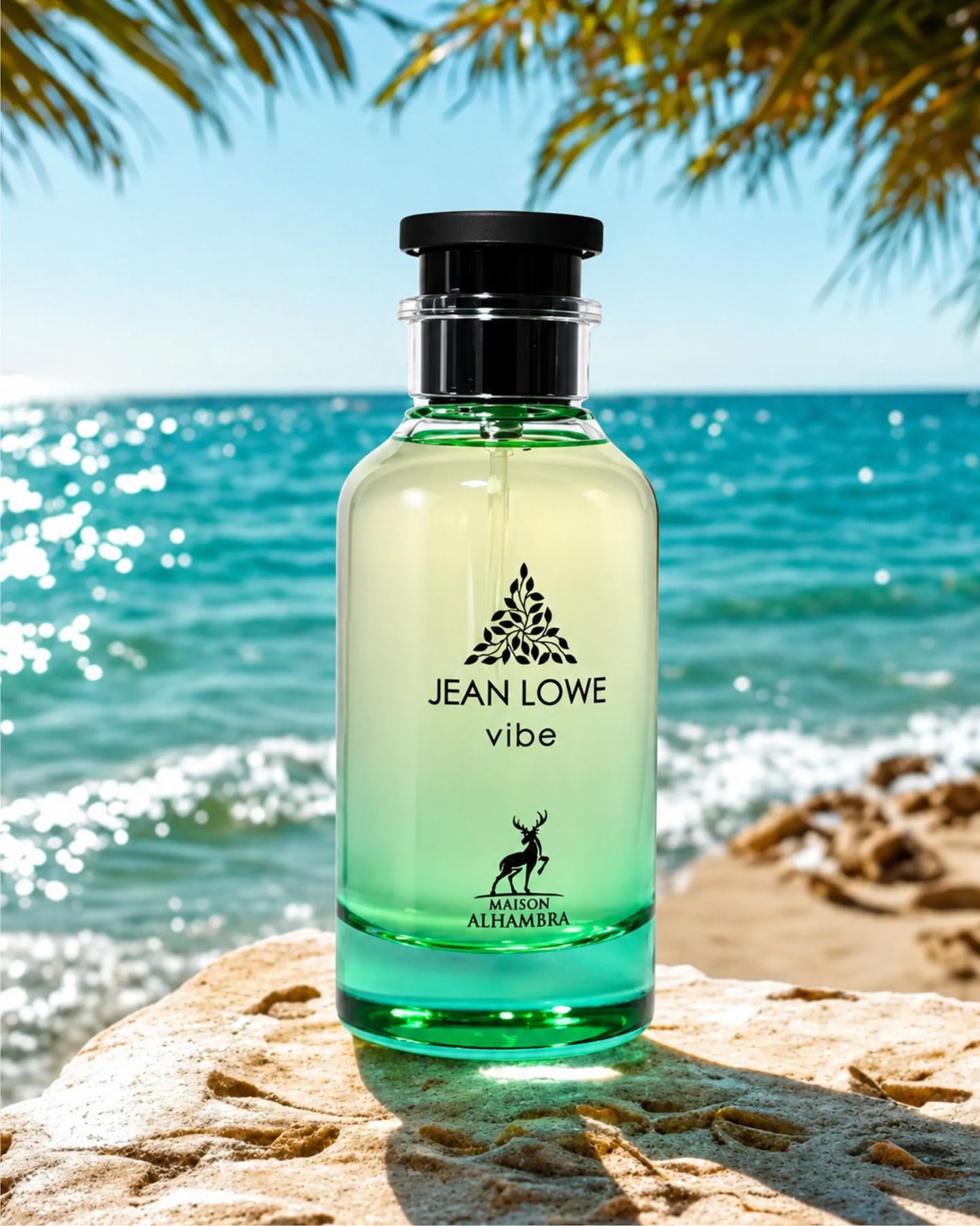 jean Lowe Vibe Eau de Parfum by Maison Alhambra placed on a rock at a tropical beach with clear blue ocean water and palm leaves in the background.