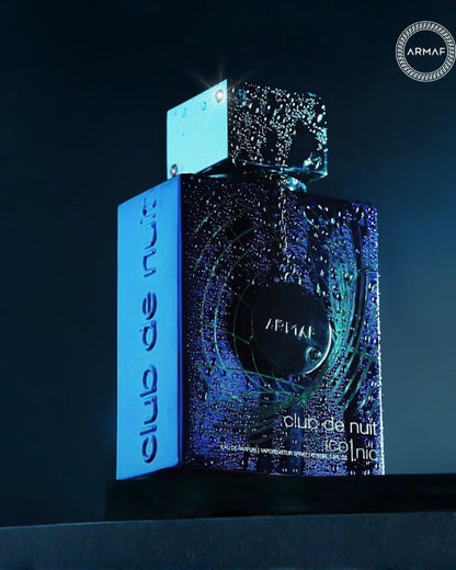 Dramatic close-up of the Armaf Club de Nuit Iconic Edp perfume bottle covered in water droplets under low, blue lighting, highlighting the texture and design.