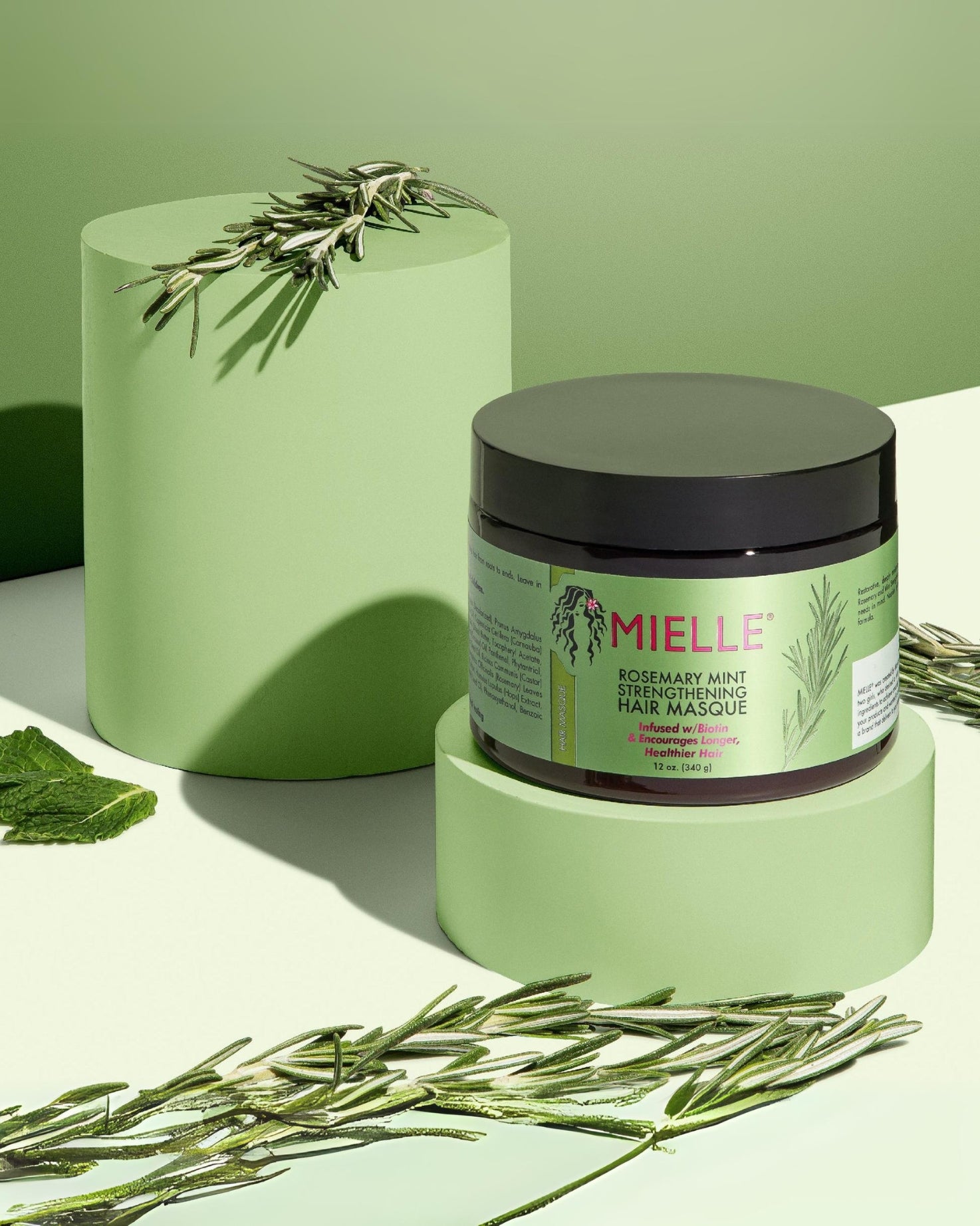 Mielle Organics Rosemary Mint Strengthening Hair Masque bottle photograph surrounded with rosemary mints