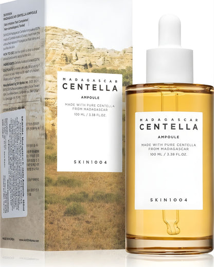 The SKIN1004 Madagascar Centella Ampoule (100 mL) bottle standing next to its earthy-toned outer box packaging. The box includes information like "Skin Irritation Test Completed" and "Non-Comedogenic Tested.