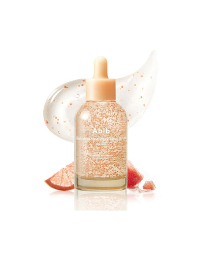 An artistic product shot of the Abib Glutahtiosome dark spot serum bottle with visible orange vita drops, set against a swipe of gel and slices of grapefruit.