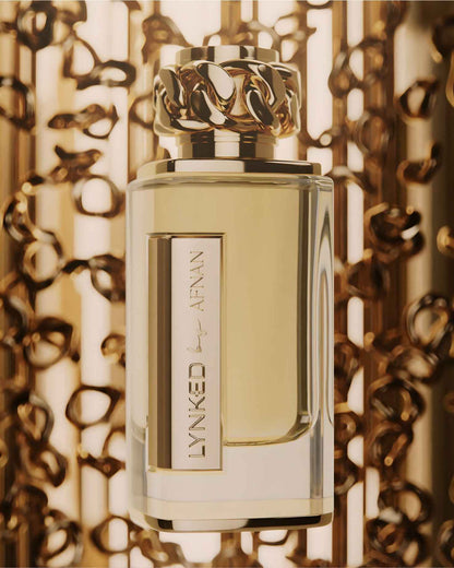 A close-up artistic shot of Afnan Lynked forever edp perfume featuring the signature gold chain-link cap, set against a warm, blurred background of golden light and bokeh patterns for a luxury aesthetic.