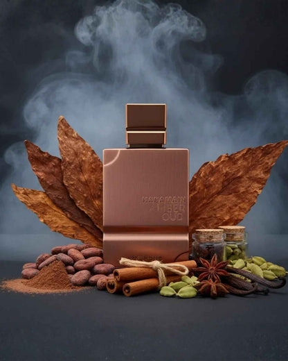 Al Haramain Amber Oud Tobacco Edition bottle surrounded by raw ingredients including dried tobacco leaves, cinnamon sticks, star anise, cardamom, and cocoa beans with a smoky background.
