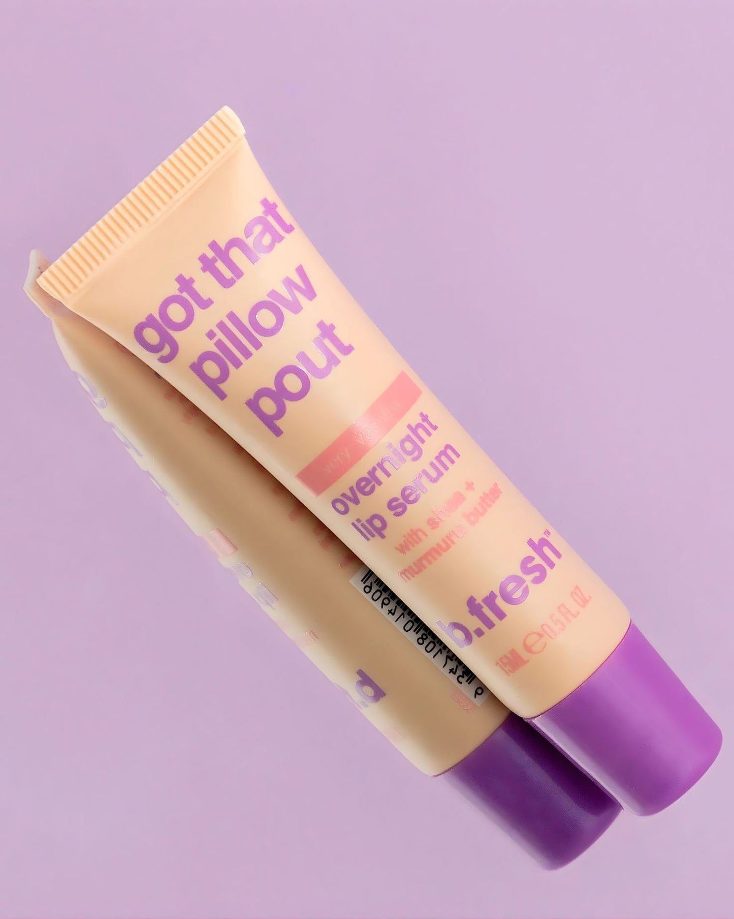 A close-up studio shot of the b.fresh Overnight Lip Serum tube, a light peach color with a purple cap. The text on the tube reads "got that pillow pout," "very vanilla," and "with shea + murumuru butter.