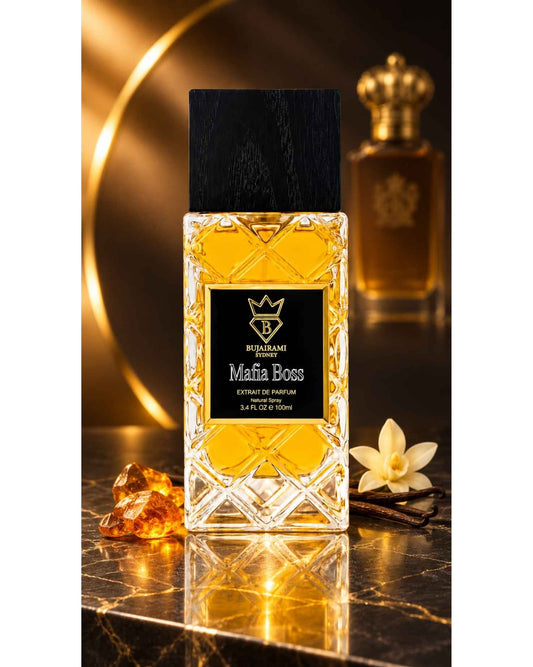 Bujairami Sydney Mafia Boss Extrait de Parfum bottle set on a marble surface alongside amber resin crystals, vanilla pods, and a white vanilla flower.