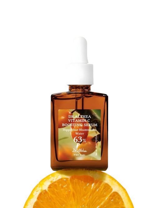 Dr. Althea Vitamin C Boosting Serum in a brown dropper bottle, placed on top of a sliced orange.
