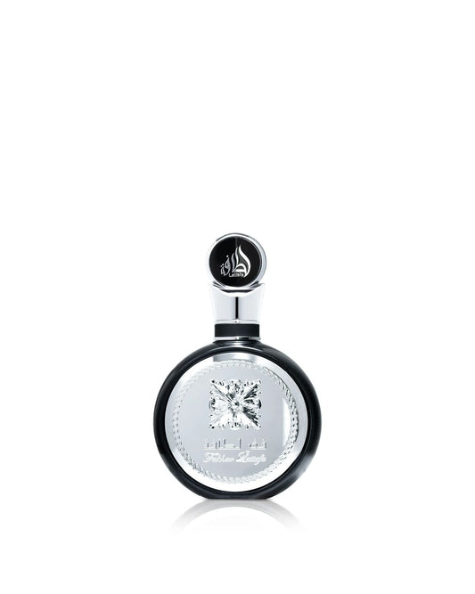 A close-up product shot of the Lattafa "Fakhar Lattafa" perfume bottle, which is round and black with a large, ornate central silver panel and an abstract diamond emblem, isolated against a white background.