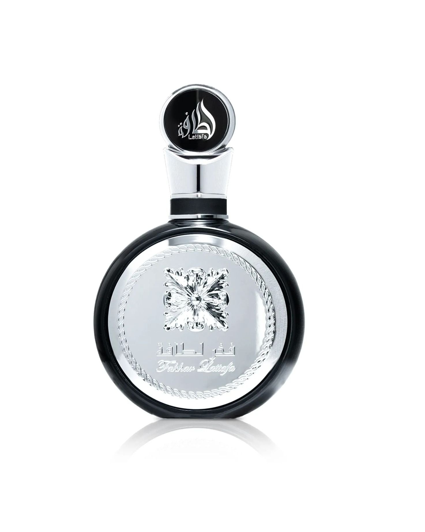 A close-up product shot of the Lattafa "Fakhar Lattafa" perfume bottle, which is round and black with a large, ornate central silver panel and an abstract diamond emblem, isolated against a white background.