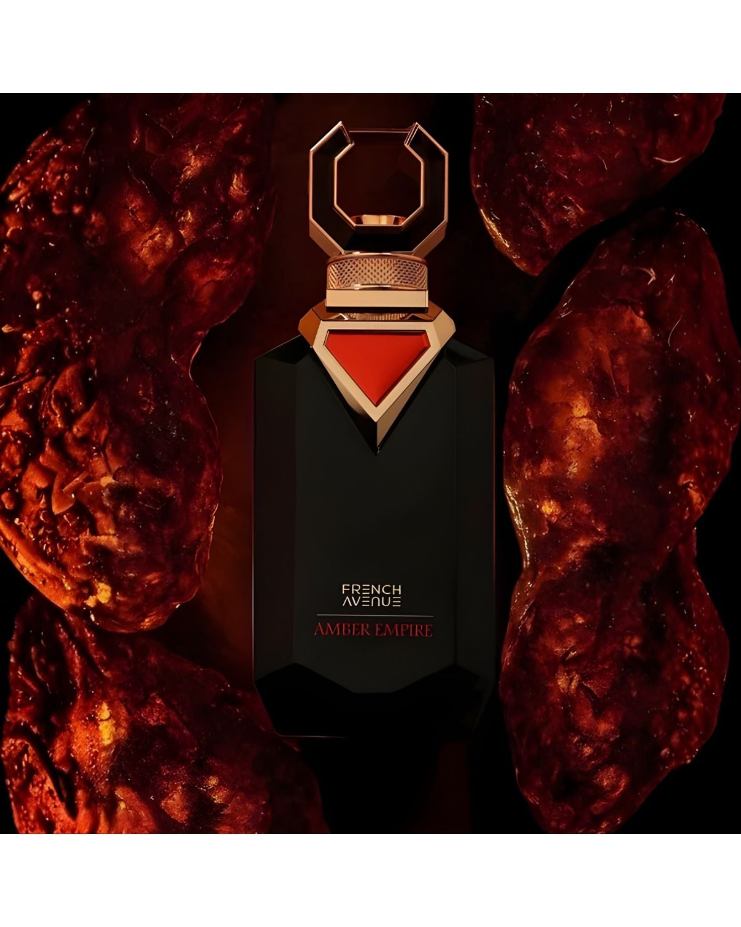 The black, faceted 'French Avenue Amber Empire' perfume bottle, with its gold cap and red triangle accent, is displayed on a dark background surrounded by four large, glowing pieces of raw amber, highlighting the fragrance's core ingredient.