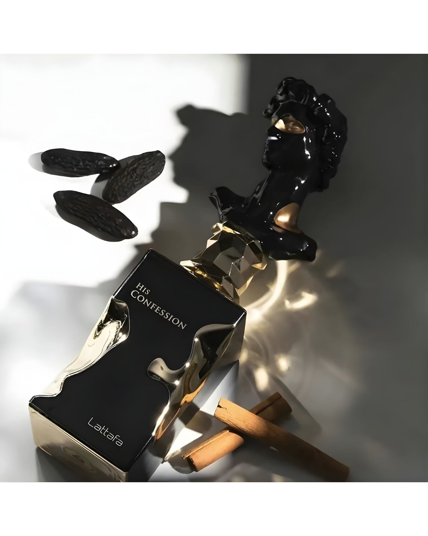 Close-up of Lattafa His Confession perfume bottle, featuring a black and metallic gold design, next to a black sculpture of a classical bust, whole tonka beans, and cinnamon sticks, highlighting the rich, spicy notes.