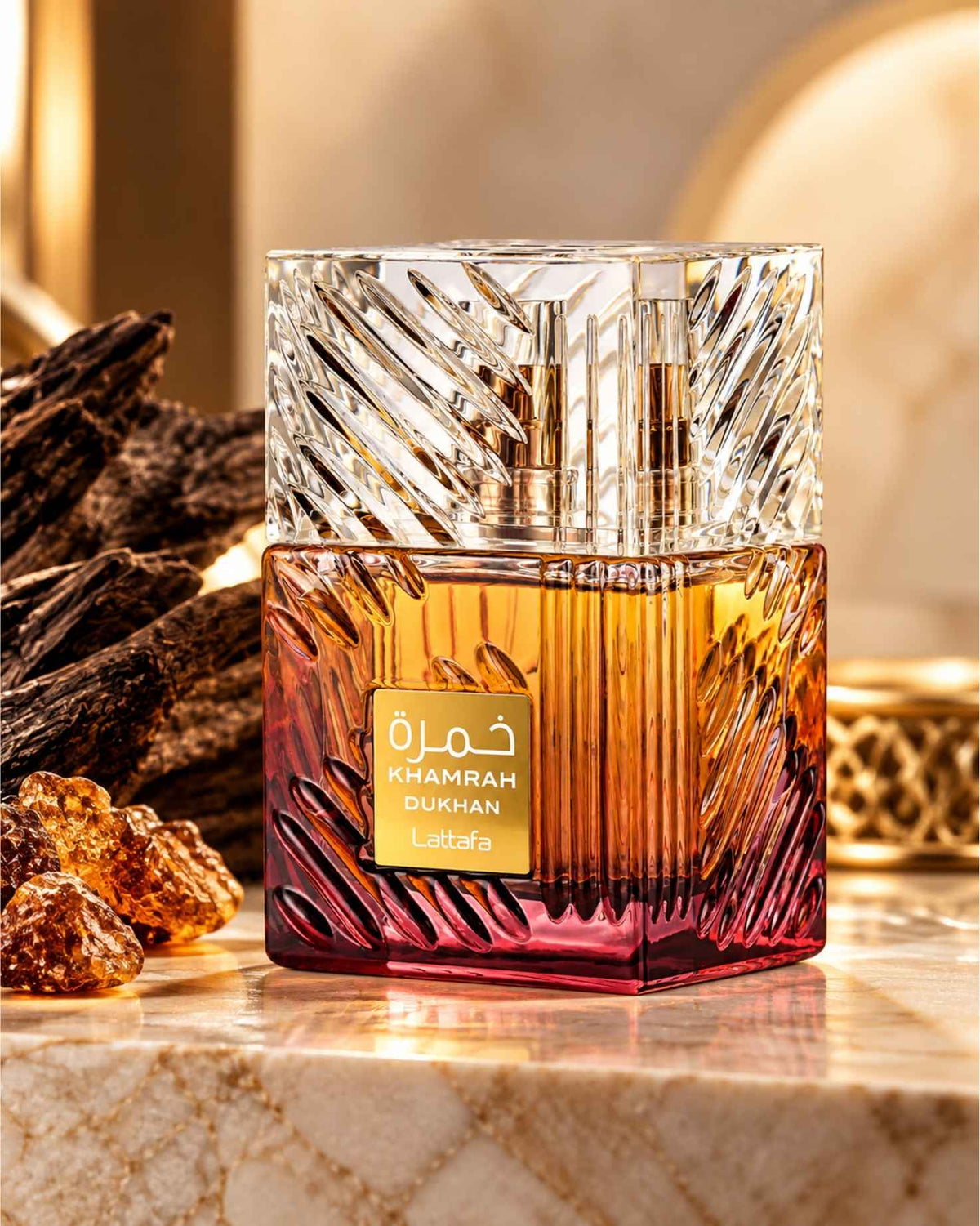 Lattafa Khamrah Dukhan Eau de Parfum bottle with crystal-cut cap displayed on marble alongside dark oud wood and amber resins.