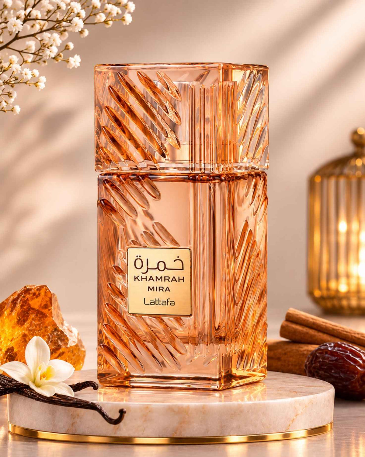 Lattafa Khamrah Mira Eau de Parfum bottle on a round marble tray surrounded by visual scent notes including amber resin, vanilla flower, vanilla pods, cinnamon sticks, and dates.