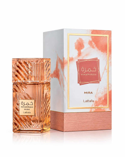 Lattafa Khamrah Mira Eau de Parfum amber carved glass bottle standing next to its white and peach marbled presentation packaging box on a reflective white surface.
