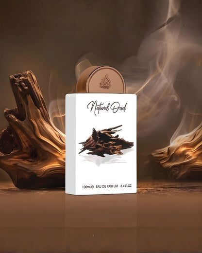 White Lattafa Natural Oud Edp perfume bottle showcased in an atmospheric setting with raw agarwood logs and a smokey brown background.