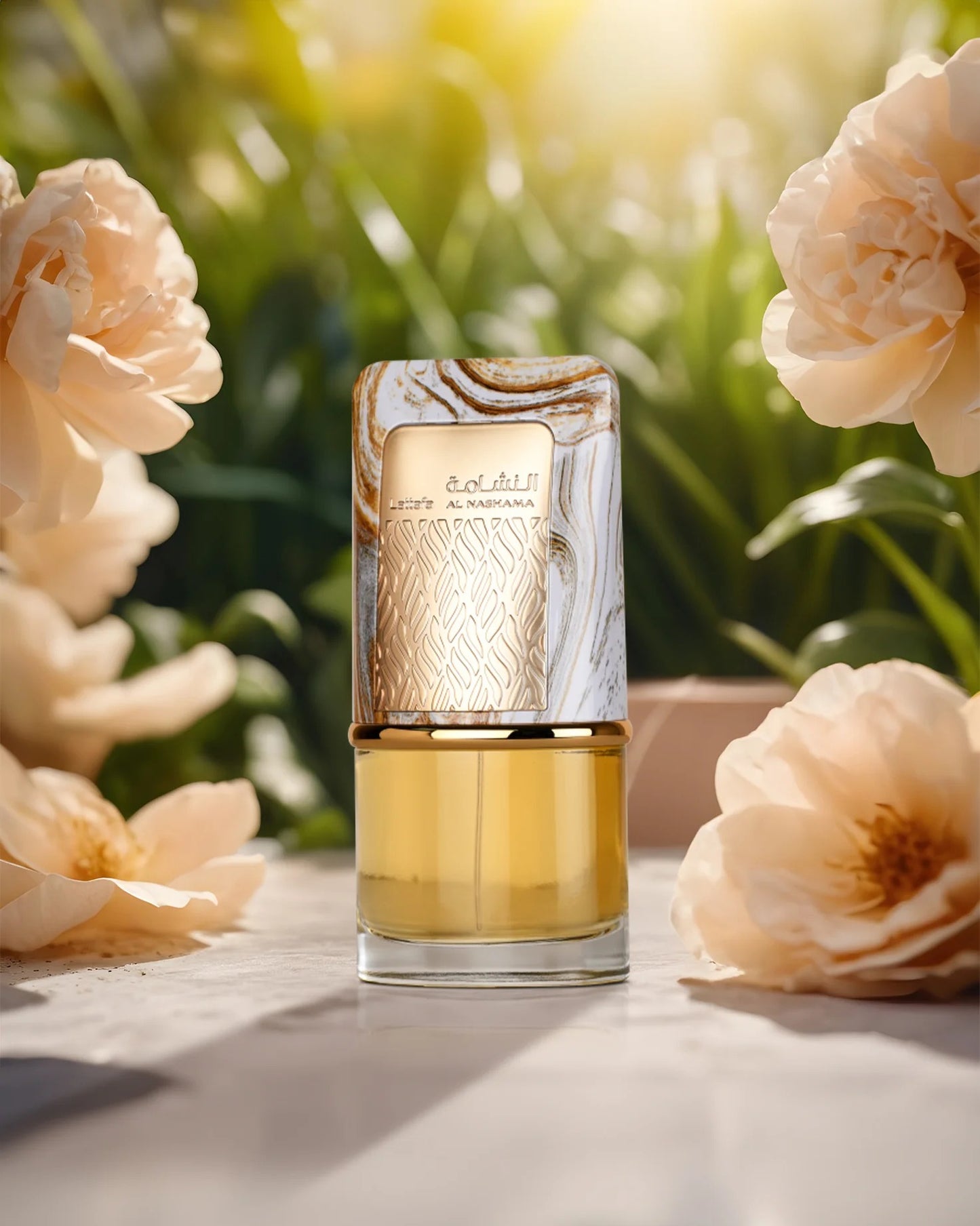 The Lattafa Al Nashama Edp perfume bottle, with its amber liquid, gold patterned body, and white/gold marble cap, is centered on a light stone surface. It is surrounded by large, soft, pale pink peony or rose flowers, set against a bright, sunlit green garden background.