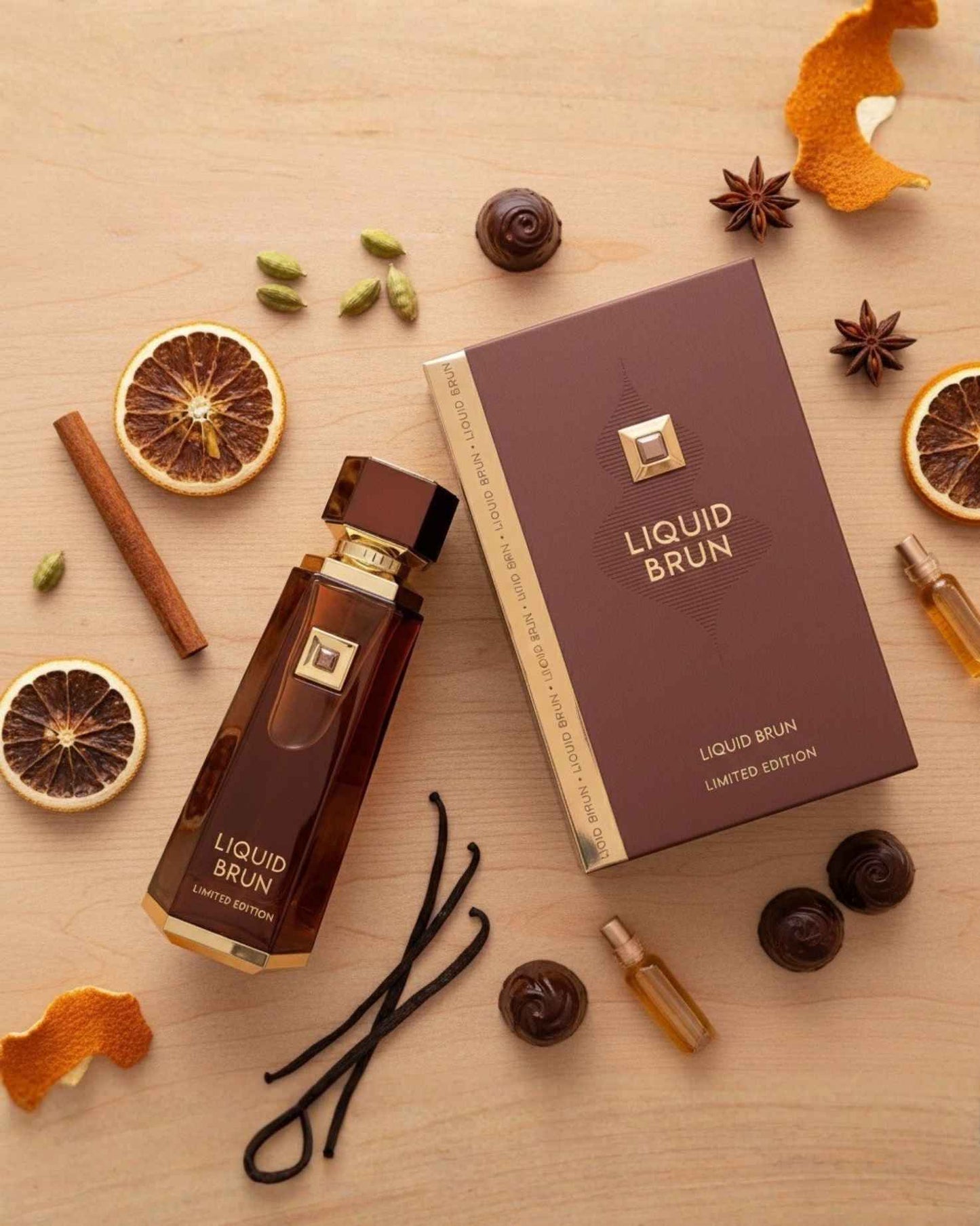 Top-down view of Liquid Brun Limited Edition perfume surrounded by fragrance notes of vanilla beans, cinnamon sticks, dried orange slices, and star anise.