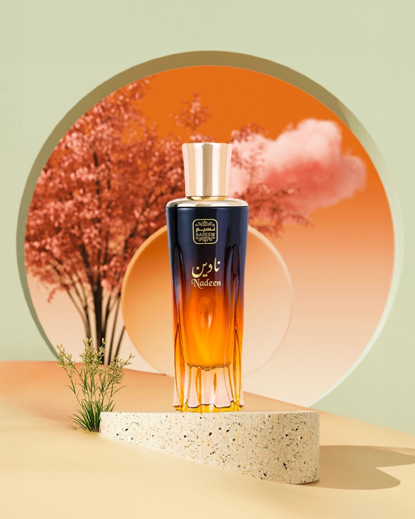 nadeen aqua parfum bottle showcased againts a artificial tree and replicate of red sun.