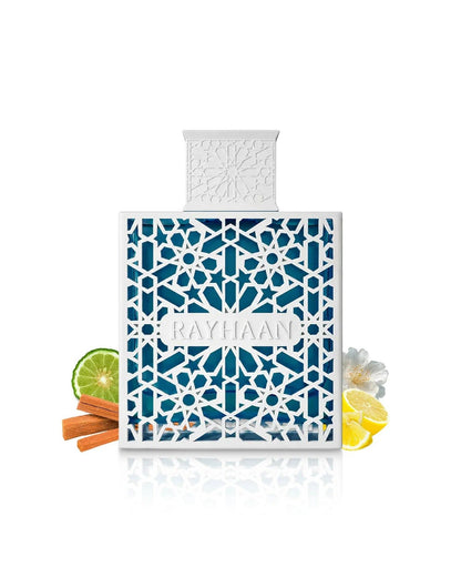 A bottle of Rayhaan Azul perfume with white geometric casing and blue liquid, surrounded by fragrance note ingredients including a lime slice, cinnamon sticks, lemon slices, and a white jasmine flower.