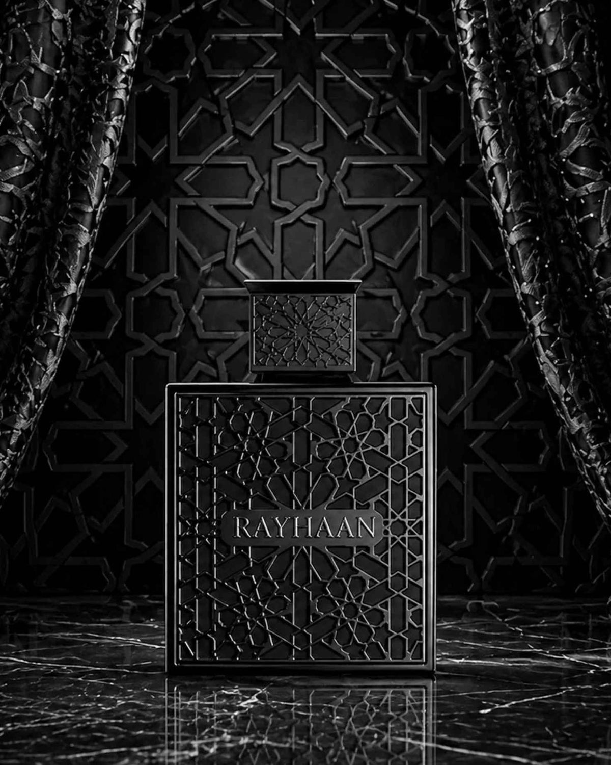 Rayhaan Obsidian Eau de Parfum black geometric latticed bottle displayed on reflective dark marble framed by black drapes and an intricate Arabic geometric wall pattern.