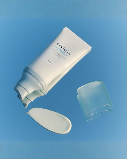 SKIN1004 Madagascar Centella Water-Fit Sun Serum in a white tube, with a swatch of the product on a reflective, light blue surface next to the clear cap.