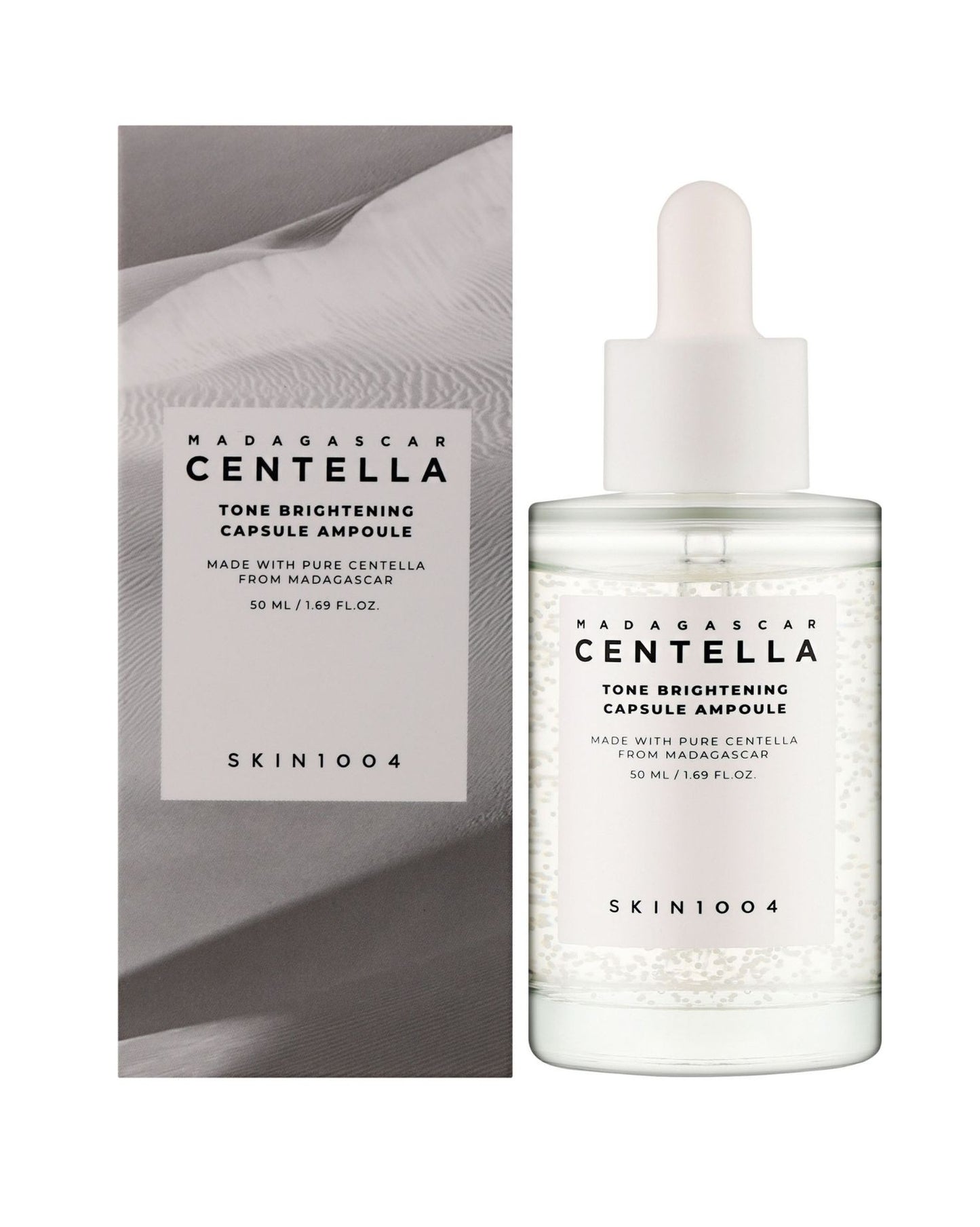 The SKIN 1004 Madagascar Centella Tone Brightening Capsule Ampoule (50 mL) is shown next to its packaging box, which features a grayscale desert or dune pattern.