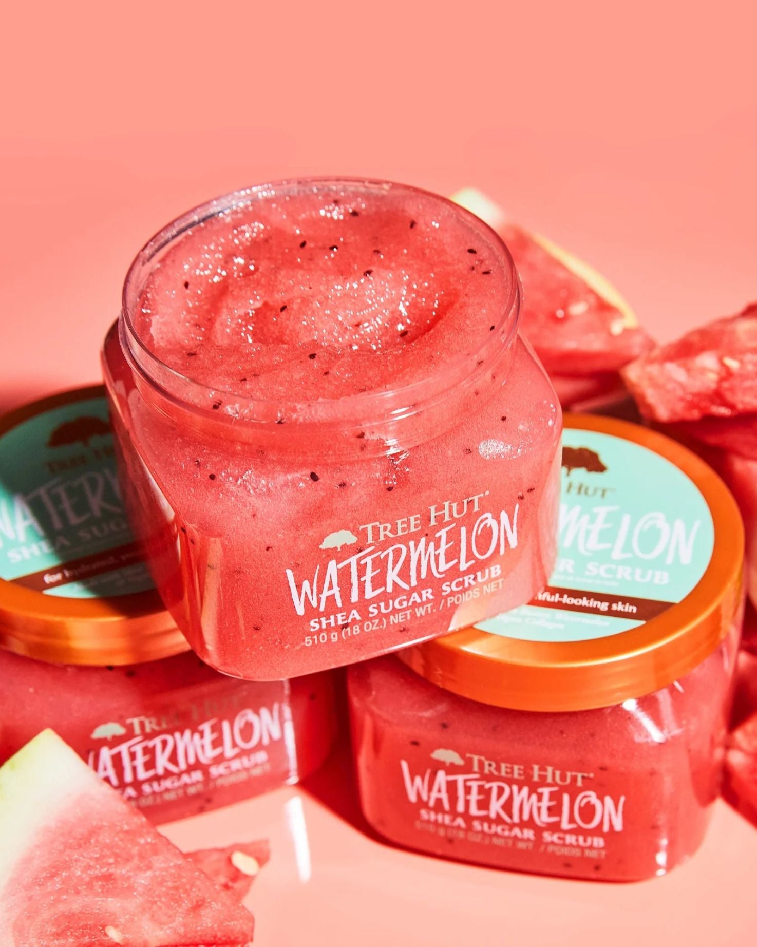 Multiple open and closed jars of Tree Hut Watermelon Shea Sugar Scrub, a hydrating body exfoliator.
