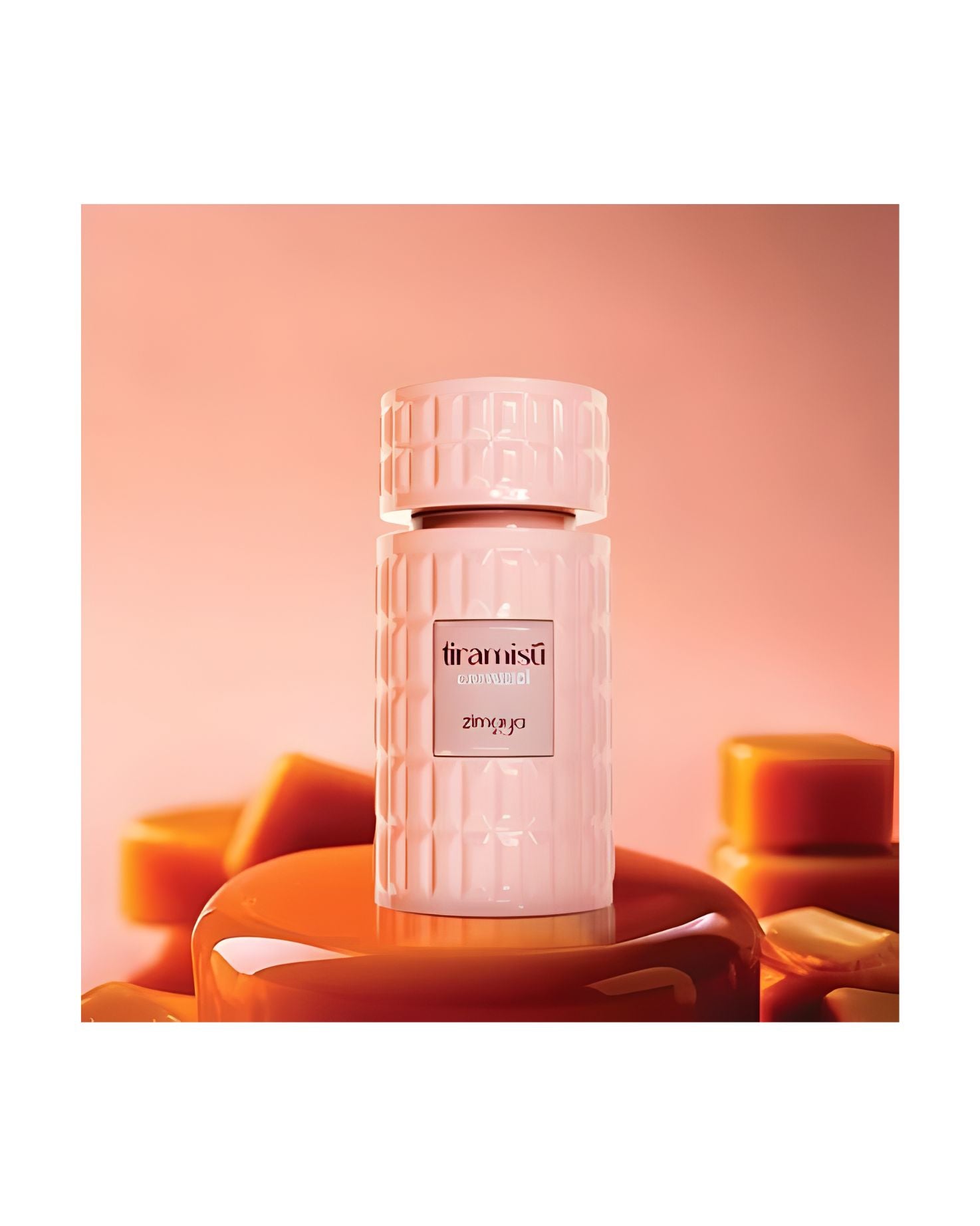 Pink, textured perfume bottle labeled 'Tiramisû' by Zimaya, resting on a glossy caramel-colored pedestal, surrounded by out-of-focus caramel candies on an orange-pink background.